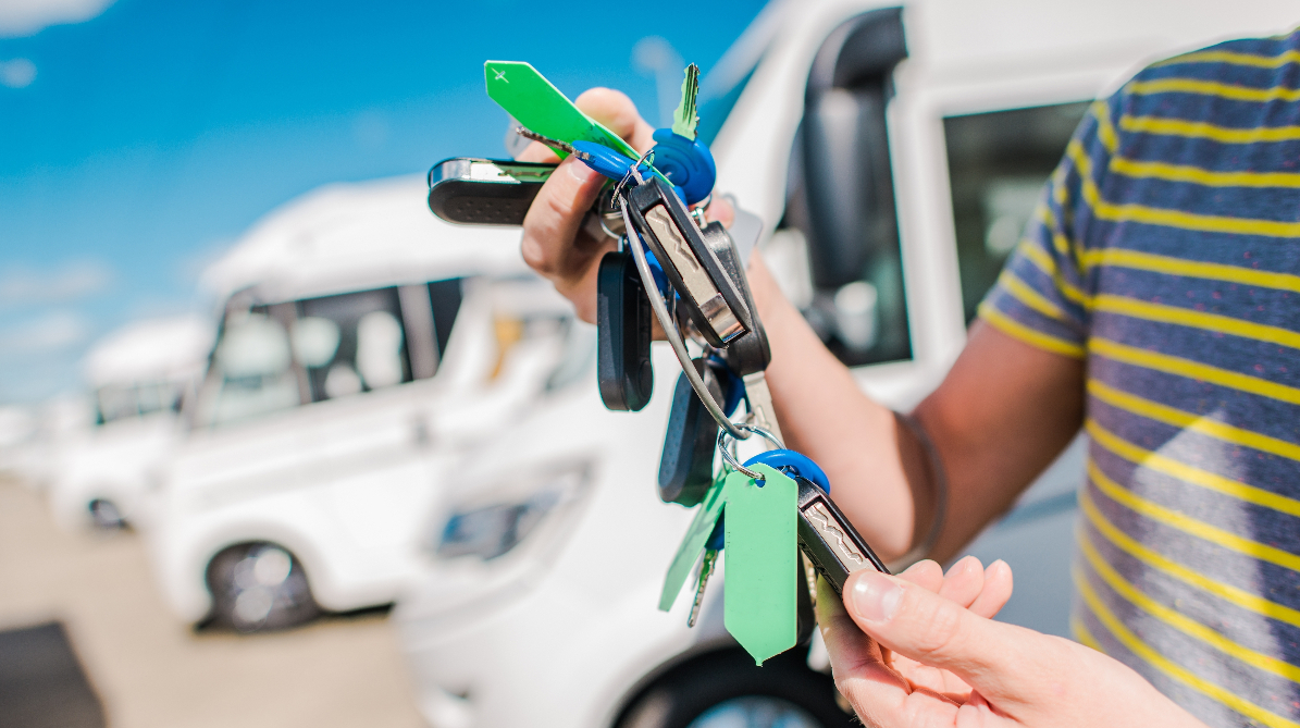 A man looking at the keys for his new RV with a few RVs in the background